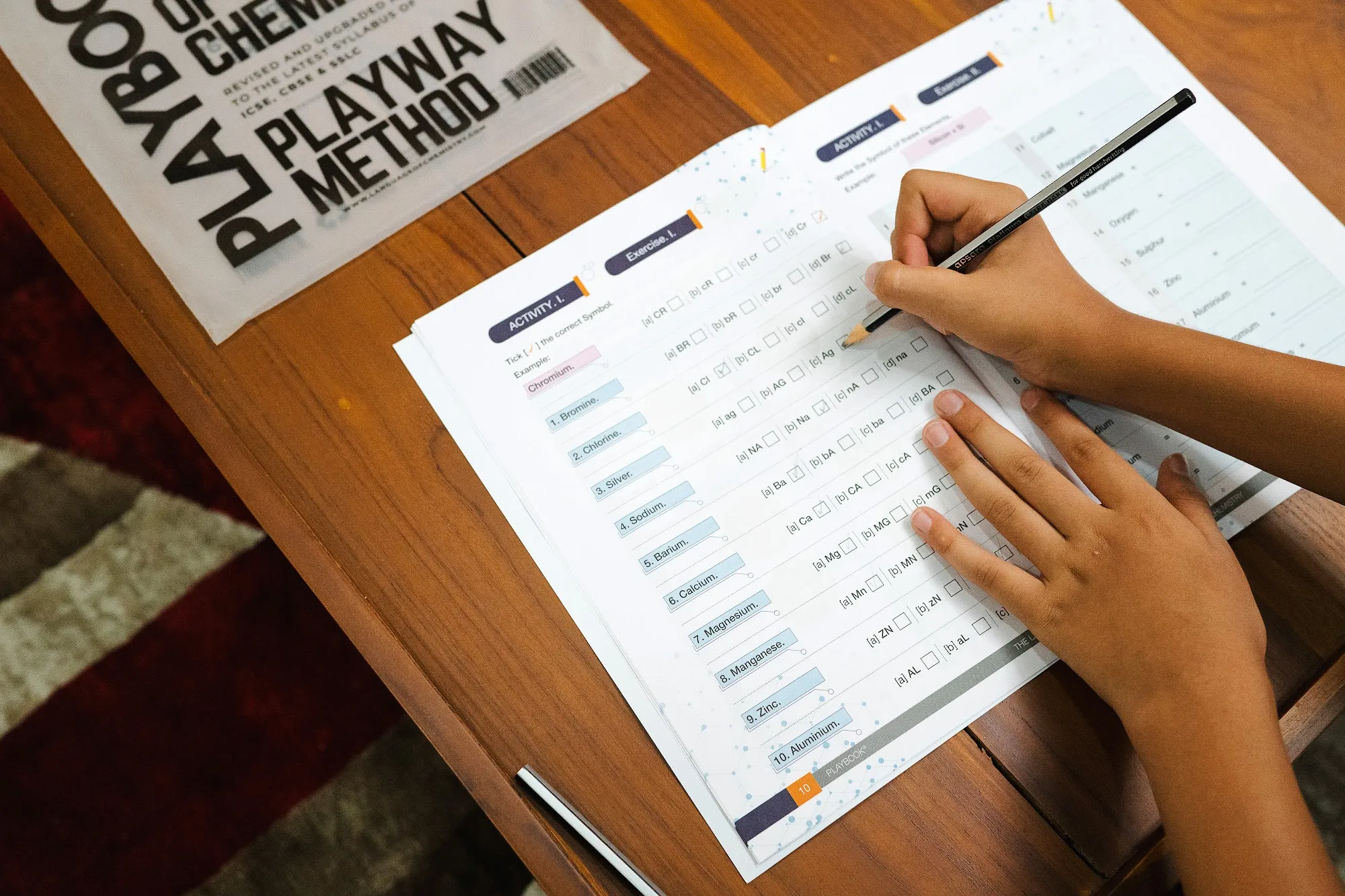 A student’s hand mid-exercise, pencil in hand, ticking symbols on the Activity I page.